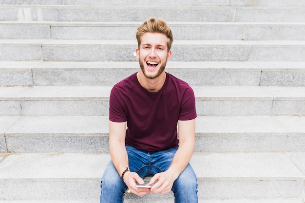 Portrait eines lächelnden jungen Mannes mit Smartphone