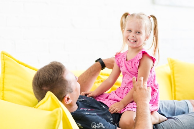 Kostenloses Foto portrait eines lächelnden mädchens mit ihrem vater auf sofa