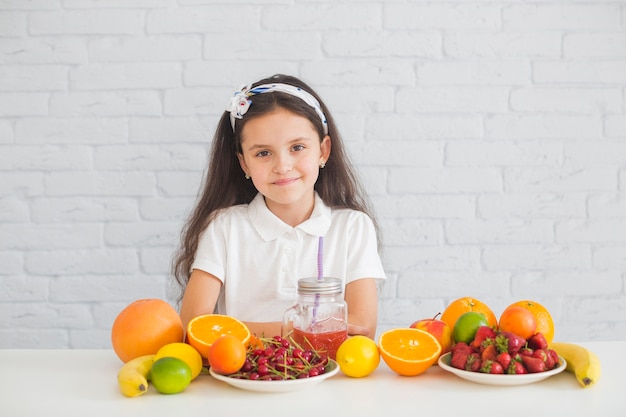 Portrait eines Mädchens mit bunten reifen Früchten auf dem Schreibtisch