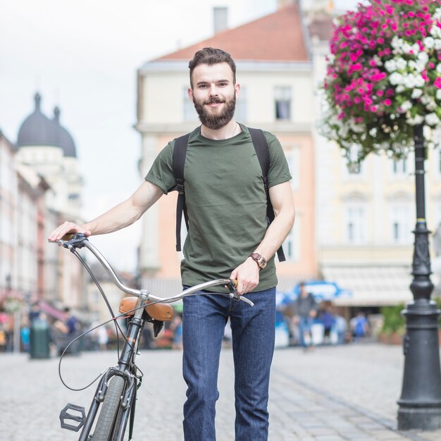 Portrait eines Mannes mit dem Fahrrad, das in Stadt geht