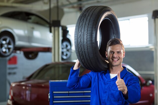 Portrait Mechaniker einen Reifen trägt