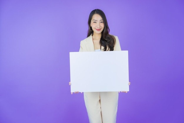 Portrait schöne junge Asiatin mit leerer weißer Plakatwand auf farbigem Hintergrund