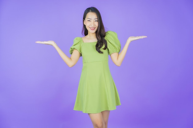 Portrait schöne junge asiatische Frau lächelt mit Aktion auf farbigem Hintergrund