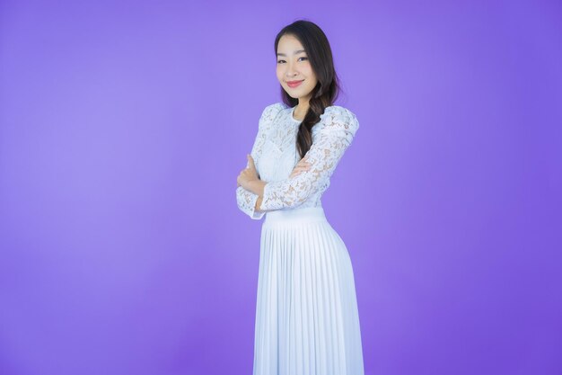 Portrait schöne junge asiatische Frau lächelt mit Aktion auf farbigem Hintergrund