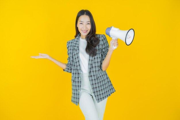 Portrait schöne junge asiatische Frau lächelt mit Megaphon auf farbigem Hintergrund