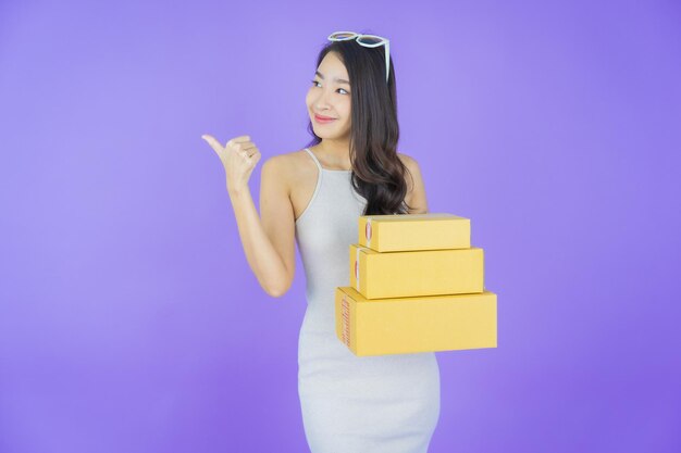 Portrait schöne junge asiatische Frau mit Box bereit für den Versand auf farbigem Hintergrund