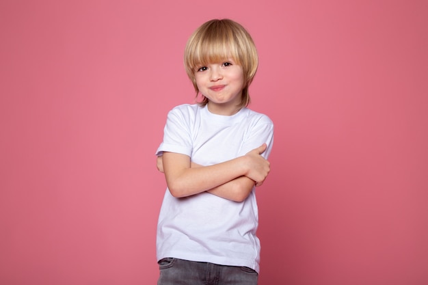 Posing Junge mit urkomischem Ausdruck auf seinem Gesicht, der die Kamera auf rosa Wand betrachtet
