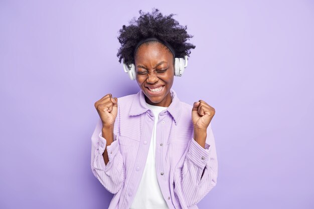 Positive erfolgreiche Afro-Amerikanerin ballt Fäuste vor Freude hört neue Musik-Playlist über kabellose Kopfhörer