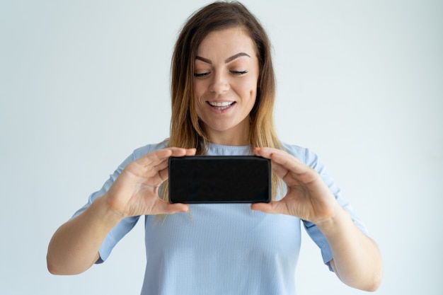 Positive erwachsene Frau, die Smartphoneschirm zeigt. Lady Werbung etwas.