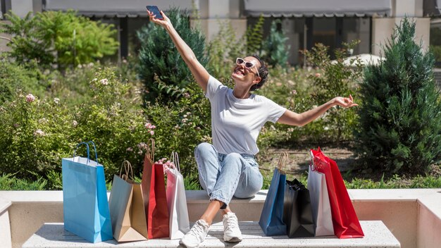 Positive Frau, die Einkaufstaschen feiert
