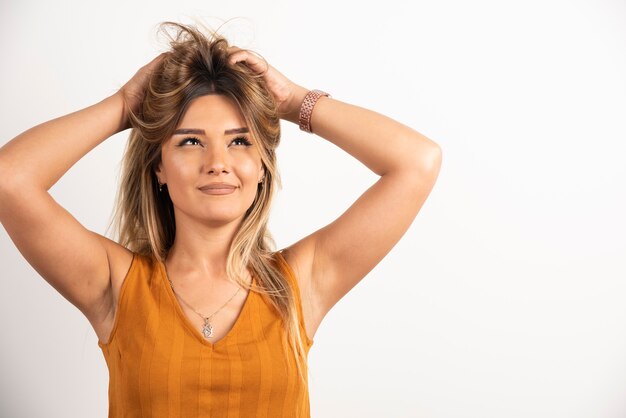 Positive Frau, die ihr Haar berührt und auf weißem Hintergrund aufwirft.