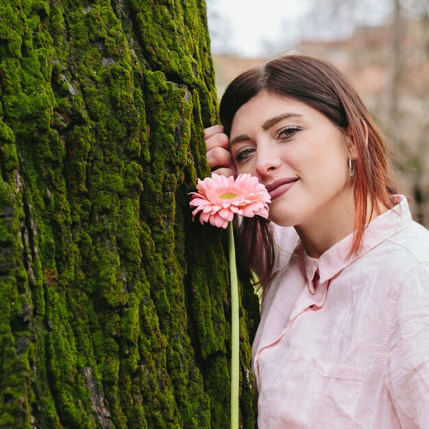 Kostenloses Foto positive frau mit blume nahe baum