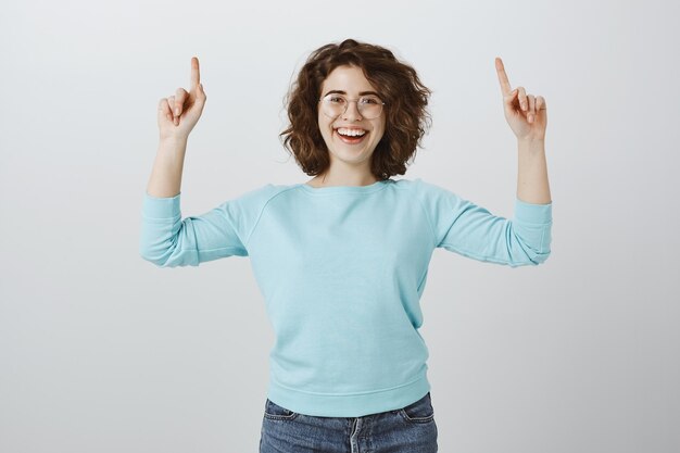 Positive glückliche Frau, die Finger nach oben zeigt und lächelt