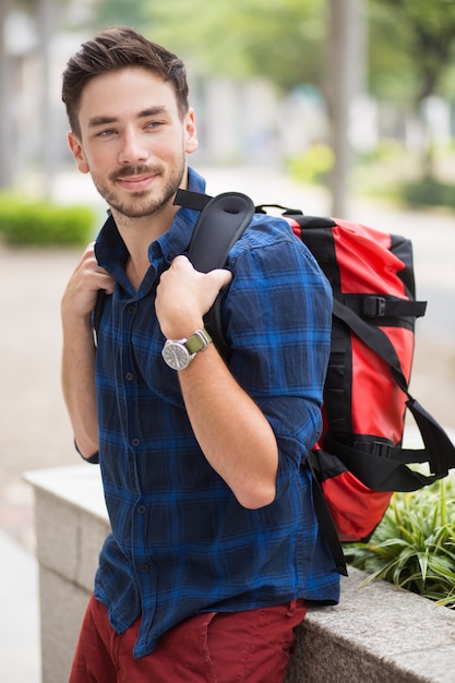 Positive Handsome Guy Sitzen auf Flowerbed in der Stadt