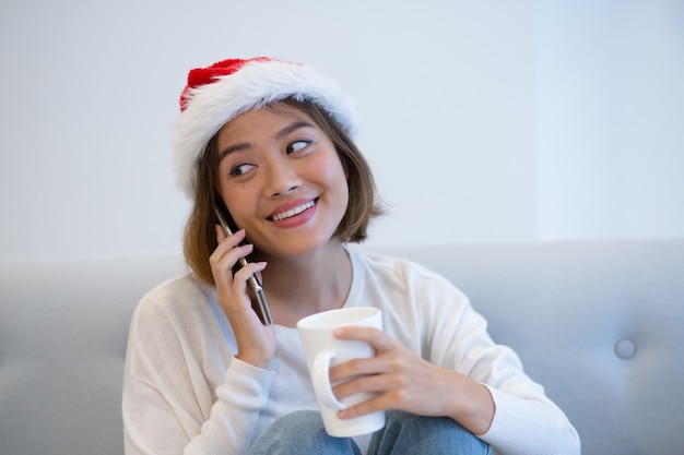 Positive hübsche Frau in Sankt-Hut sprechend am Handy