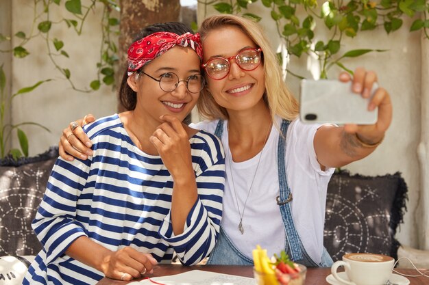 Positive interracial Frauen umarmen sich, während sie am Tisch sitzen