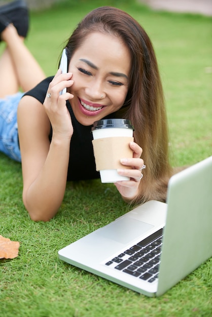 Positive junge Frau, die am Telefon spricht