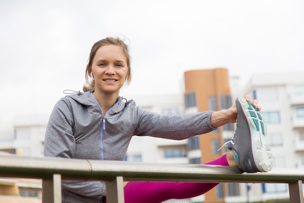 Positive junge Frau, die Bein ausdehnt