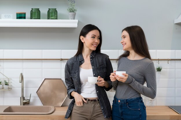 Positive junge Frauen, die zusammen Kaffee trinken