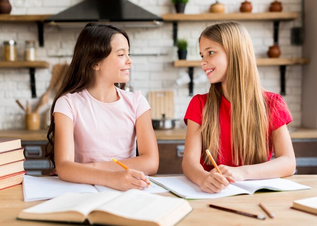 Positive Mädchen, die zusammen in Schreibhefte schreiben