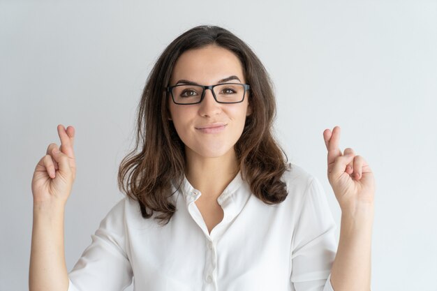 Positive nette Studentin in den Gläsern, die Wunsch machen.