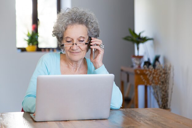 Positive pensionierte Dame, die zu Hause arbeitet