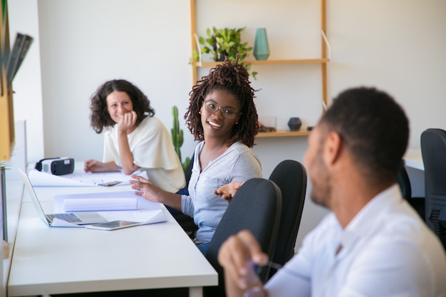 Positive vielfältige technische Arbeitsgruppen, die an Arbeitsplätzen plaudern