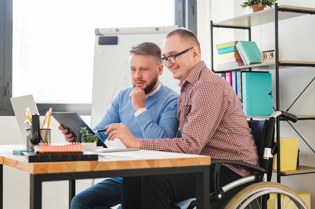 Positiver behinderter Arbeiter zusammen mit dem Manager im Büro