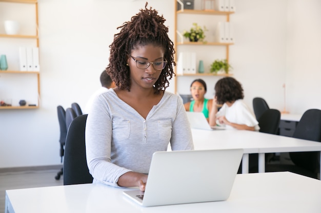 Positiver fokussierter Afroamerikanerangestellter, der an Computer arbeitet
