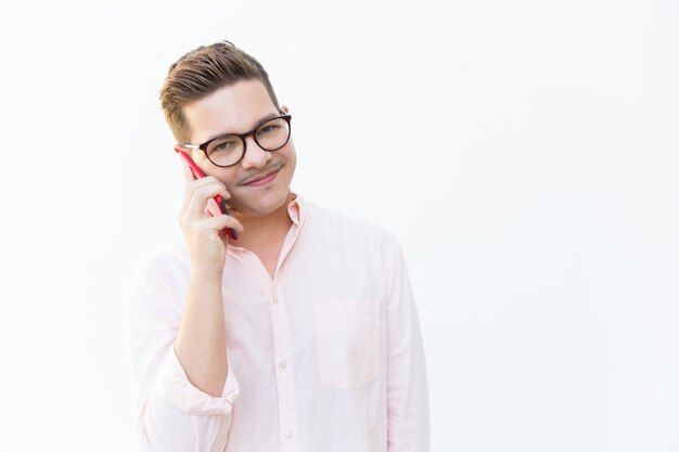 Positiver freundlicher Kerl im Eyewear sprechend auf Mobiltelefon