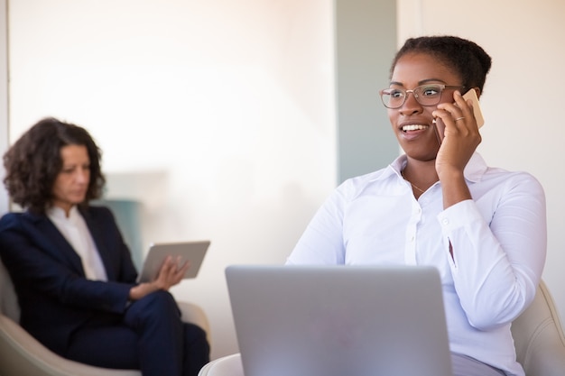 Positiver junger weiblicher Manager, der am Telefon spricht