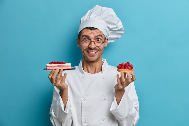 Positiver professioneller Konditor hält leckere handgemachte Desserts mit Beeren