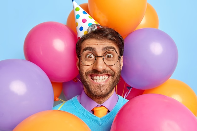 Positiver Typ, umgeben von Partyballons, die posieren