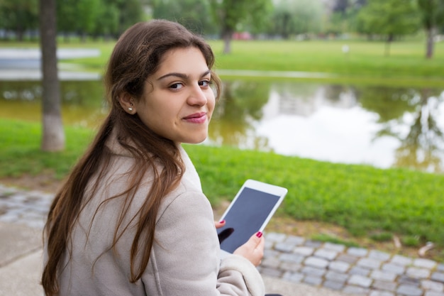 Positives lateinisches Mädchen, das online draußen plaudert