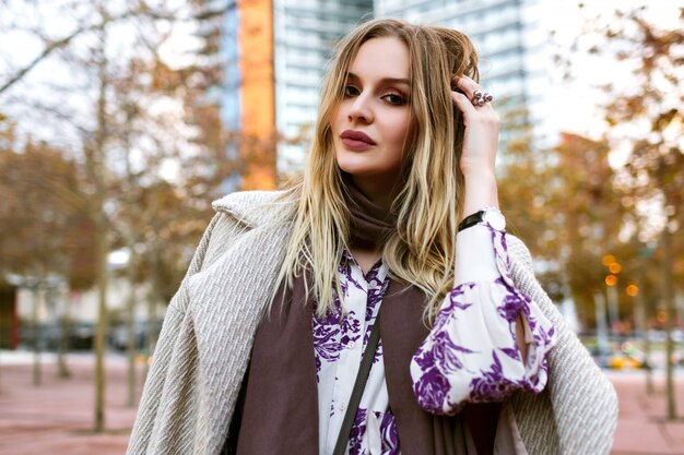 Positives Porträt des Lebensstils im Freien der hübschen blonden Frau lächelndes Ende genießen Zeit, elegantes Glamour-Outfit, Kleid und Mantel tragend, warme Farben, Frühlingsherbstzeit.