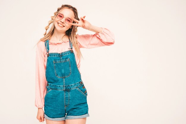 Positives und lustiges Model posiert auf grauer Wand im Studio mit Sonnenbrille