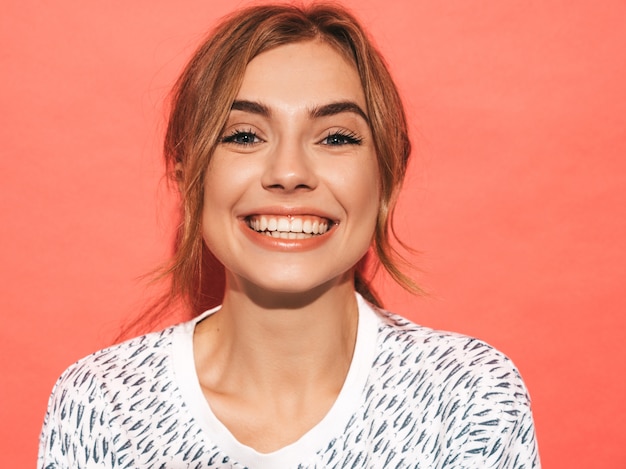 Positives weibliches Lächeln. Lustiges Modell, das nahe rosa Wand im Studio aufwirft