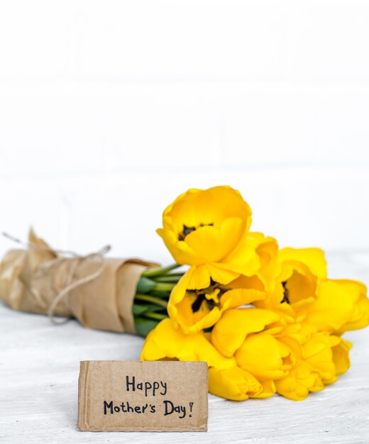 Postkarte Muttertag und gelbe Tulpen auf Holz