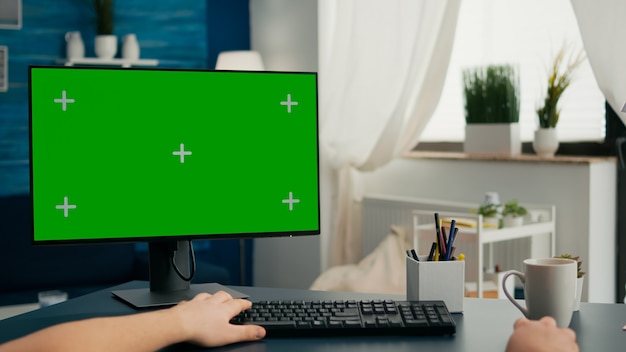 POV eines kaukasischen Mannes, der an einer Geschäftskonferenz mit isoliertem PC arbeitet. Mann, der Computer mit Mock-up-Greenscreen-Chroma-Key auf dem Schreibtisch im Wohnzimmer betrachtet