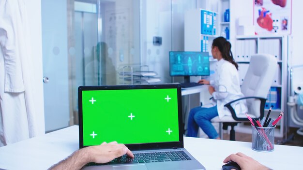 Pov-Laptop-Display mit grünem Modell im Krankenhausschrank. Arzt, der die Glastür der Klinik öffnet. Arzt mit Notebook mit Chroma-Key auf dem Display in der medizinischen Klinik.