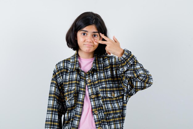 Preteen Mädchen mit V-Zeichen über Auge im Hemd, Vorderansicht der Jacke.