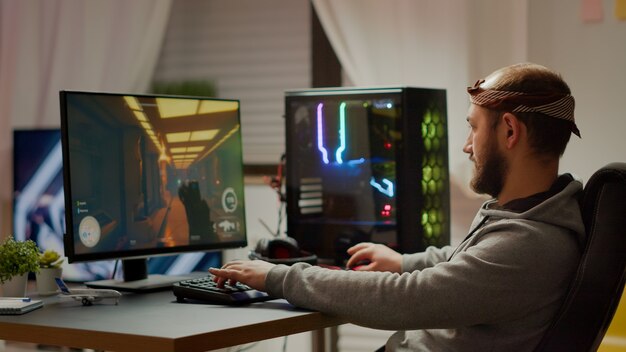 Pro eSport-Mann-Spieler, der in die Kamera lächelt und Ego-Shooter-Videospielspiele auf einem virtuellen Meisterschaftsereignis spielt. Online-Streaming von Cyber-Performances auf einem leistungsstarken PC während des Turniers
