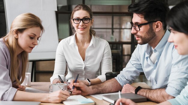 Professionelle Geschäftsfrau mit Brille während eines Treffens mit ihren Mitarbeitern