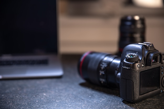 Kostenloses Foto professionelle kamera auf einem unscharfen hintergrund mit einem laptop