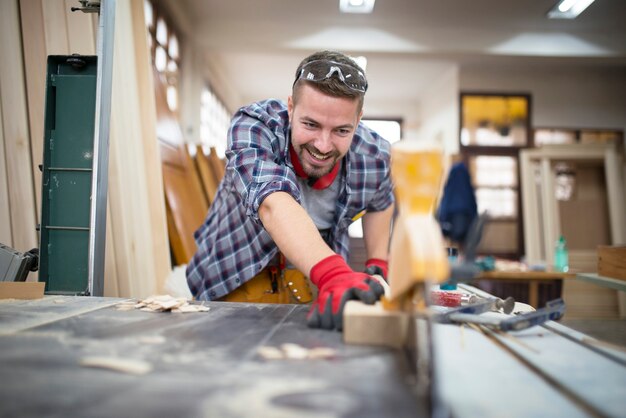Professionelle lächelnde Handwerker-Schneidanlage auf kreisförmiger Maschine in der Holzbearbeitungswerkstatt