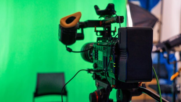 Professionelle Videokamera auf einem Stativ mit grünem Chromakey in einem Studio