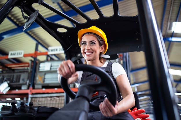 Professionelle weibliche Industriefahrerin, die Gabelstaplermaschine im Fabriklager betreibt