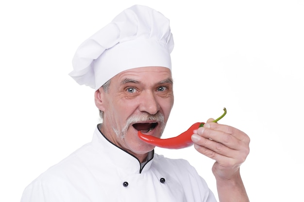 Professioneller älterer Koch mit rotem Pfeffer auf weißer Wand. Glücklicher Koch mit Gemüse