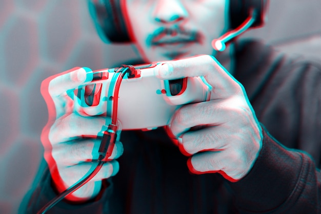 Professioneller eSport-Gamer, der ein Spiel mit Gaming-Controller im Doppelfarbbelichtungseffekt spielt