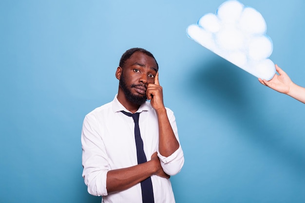 Professioneller Geschäftsmann, der unter Weißbuch denkt, dachte Blasenkonzept, das mit verschränkten Armen und dem Finger auf den Kopf zeigt. Afroamerikanischer Unternehmer Brainstorming neben der Ideenwolke.